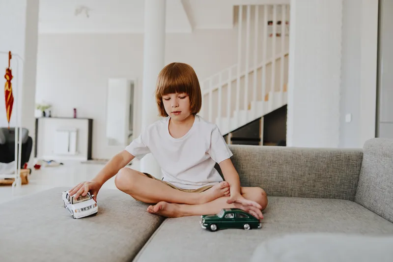 Young boy playing with toy cars in a cozy living room, showcasing his creativity and imagination in a relaxed environment filled with natural light.