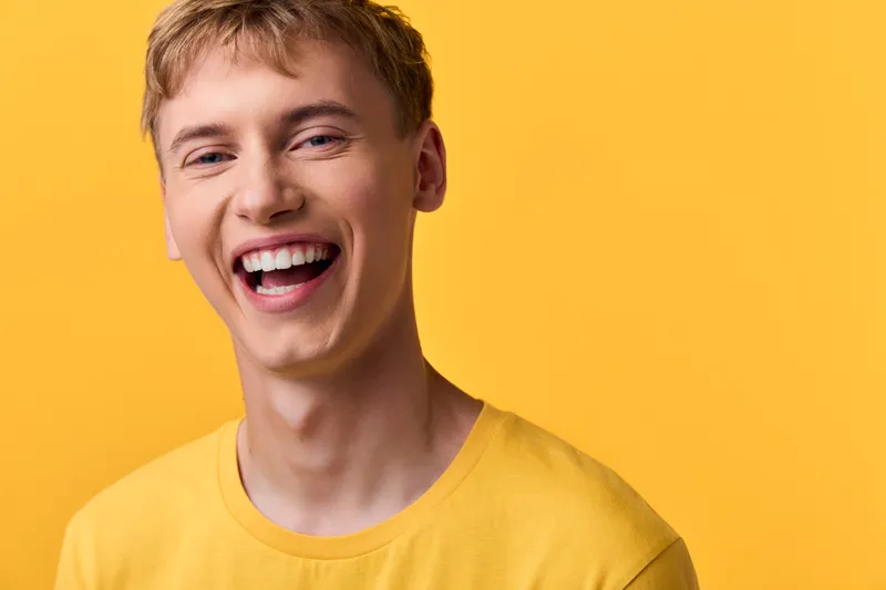 Smile, young man in a yellow tee against a bright yellow background, showcasing cheerful emotion and casual style for lifestyle, advertising and positive impact creative concepts