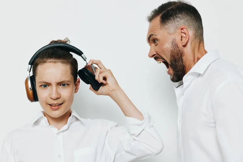 Professional man shows dynamic emotions during a business moment with a younger colleague wearing headphones. The isolated white background highlights energy and leadership in a focused corporate