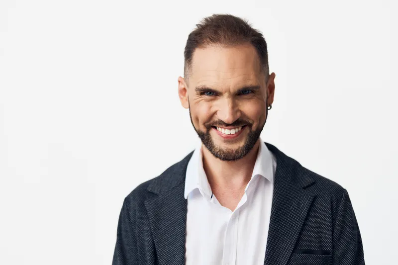 A confident business professional man poses on an isolated colored background, expressing positive emotion and approachability. Clean wardrobe and smiling demeanor convey leadership and collaboration.