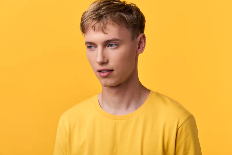 Young man, yellow background, casual clothing, studio shot, head and shoulders with a relaxed expression, bright and contemporary mood suitable for fashion, lifestyle, or branding visuals.