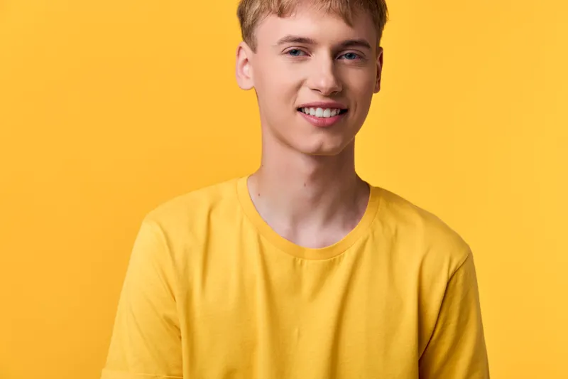 Smiling man in a yellow tee against a bold yellow background, casual fashion vibe, studio shot, warm lighting, approachable mood, everyday wear, fresh and cheerful