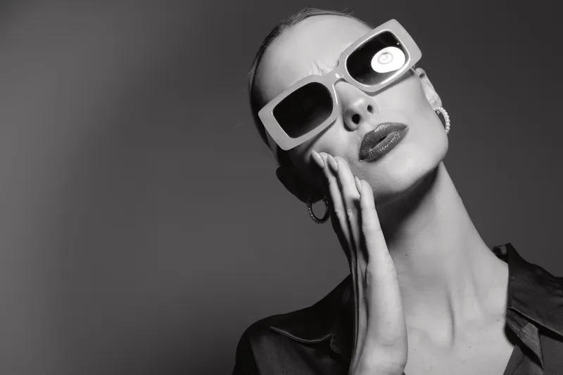 Portrait of a white woman with pale skin wearing large sunglasses and dark lipstick in black and white. Fashion concept with elegant style and confident attitude.