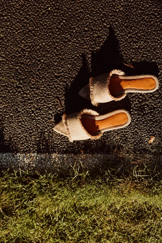 Cozy slippers resting on a gravel path beside grass, suggesting a relaxed evening routine, homey vibe, and moments of self care. Soft lighting creates warm, tranquil atmosphere and subtle sense of