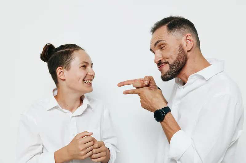 A professional man shares a candid moment with a younger colleague, showing thoughtful emotion on a bright colored backdrop. This isolated studio scene highlights collaboration, confidence, and