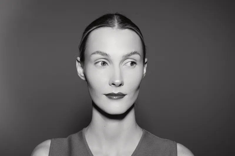 Portrait of a young white woman with pale skin looking sideways on grey background. Concept of beauty, fashion, and female model in studio lighting.