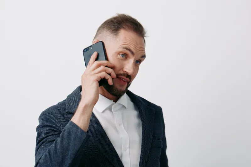 Professional man on a phone, business mood, confident and focused, posing against an isolated colored background. Expresses determination and calm, ready for a strategic call.