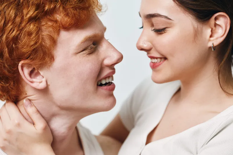 Couple, woman and man smiling close together for love, happiness and relationship. Youth and romance with affection and intimacy on white background for emotional connection.