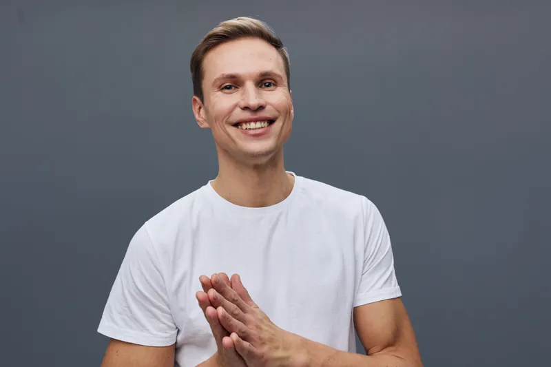 Smiling happy caucasian man wear white t-shirt look camera isolated on grey background closeup portrait positive emotion concept mental health and gadgets