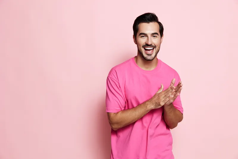 Full body smiling cheerful young man wear pink t-shirt look camera isolated on plain solid pink background studio portrait. People lifestyle concept.