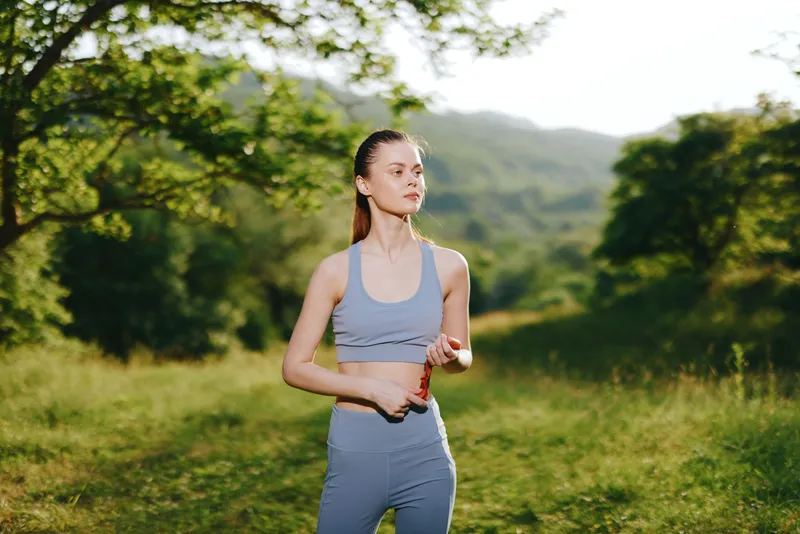 Fit young woman exercising outdoors in sportswear, enjoying nature and maintaining a healthy lifestyle in a lush green landscape