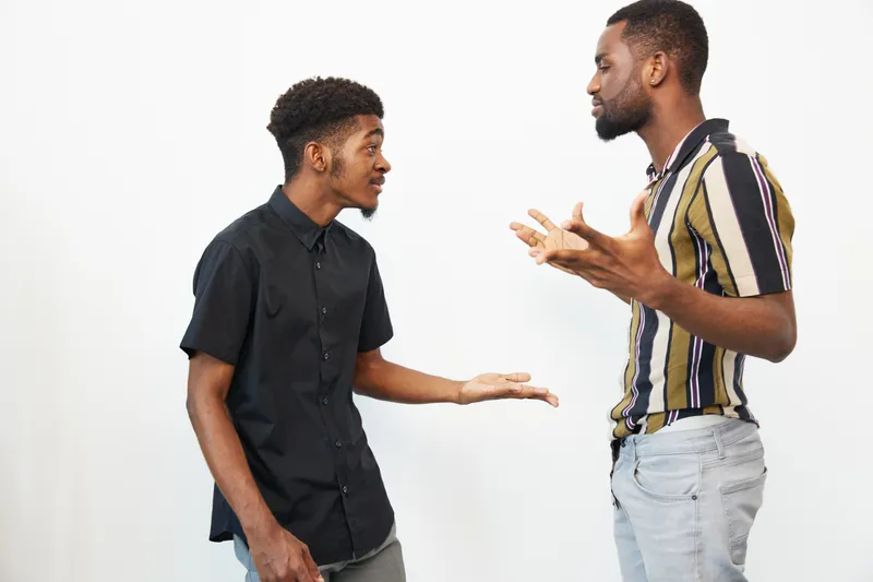 Engaging conversation between two African American men, showcasing expressions of enthusiasm and connection in a modern setting. Emphasizes communication and camaraderie.