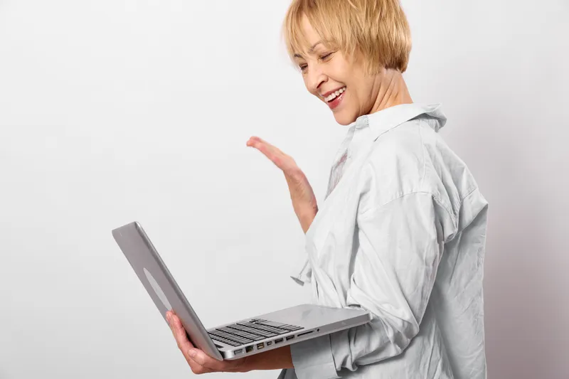 Woman profile holds laptop, typing with smile, technology workspace mood, gray shirt, isolated on white background, adult female working with computer, today
