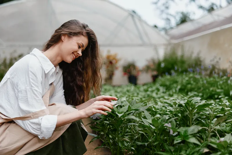 Young woman tending to plants in a greenhouse, showcasing her passion for gardening and connecting with nature Emphasizes health, wellness, and sustainability