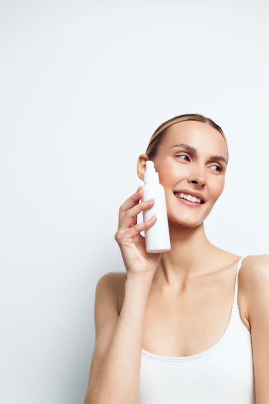 Woman holds milk glass for drinking, smiling with bright eyes, hygiene and dairy wellness portrait on clean minimal background, fresh hydration, soft light, copy space, calm mood
