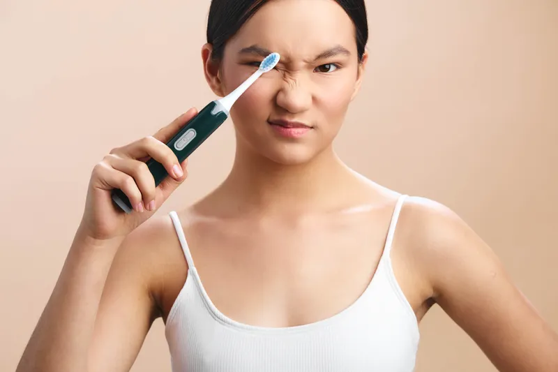an asian woman uses a digital thermometer to check her temperature in a casual home setting, her expression serious yet composed, signaling concern for health and everyday wellness while staying