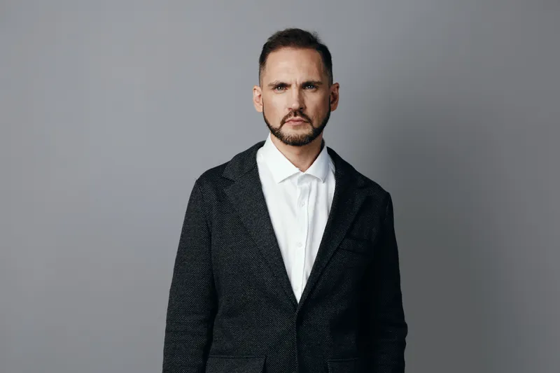 A professional man in business attire stands against a colored isolated background, exuding confidence and focus, ready for strategic decisions in a corporate setting.