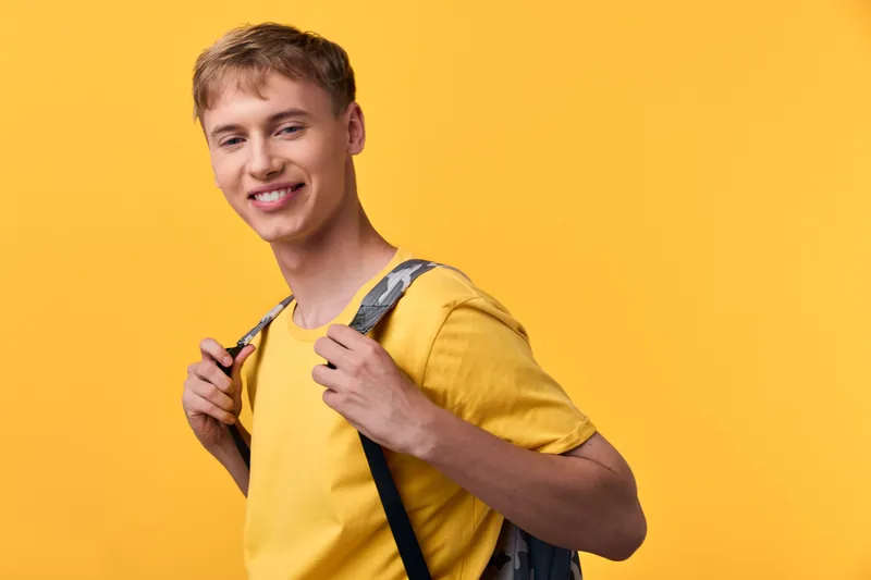 Student with backpack in a bright yellow backdrop, showcasing casual style, energy and confidence during everyday learning and exploration, ready for new challenges and opportunities in education and