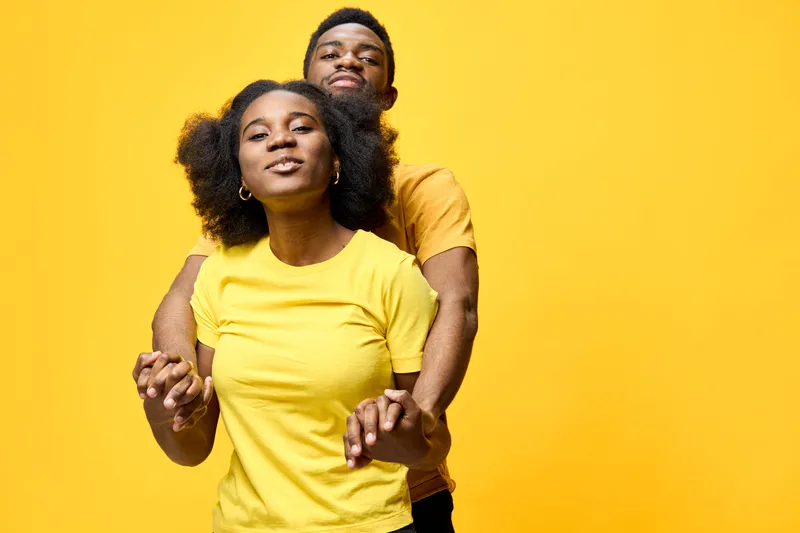 Cheerful couple in matching yellow t shirts on a bright yellow background, showcasing love and happiness in a playful and vibrant atmosphere