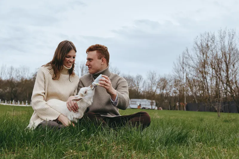 Couple outdoors with dog, affection and cozy atmosphere in a field setting, lifestyle moments of joy, grass underfoot, autumn light, candid smiles, serene countryside backdrop
