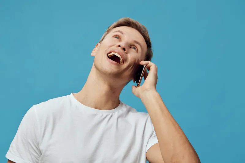 Smiling young man talking phone happy casual wear white t-shirt isolated blue background video call communication concept