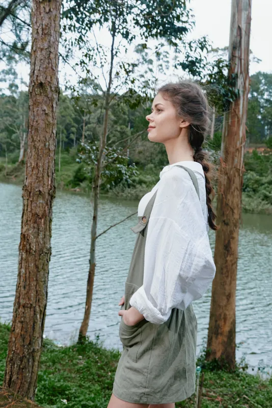 Young model in a casual outfit, exuding tranquility by the serene lake surrounded by nature, showcasing a perfect blend of style and outdoor beauty