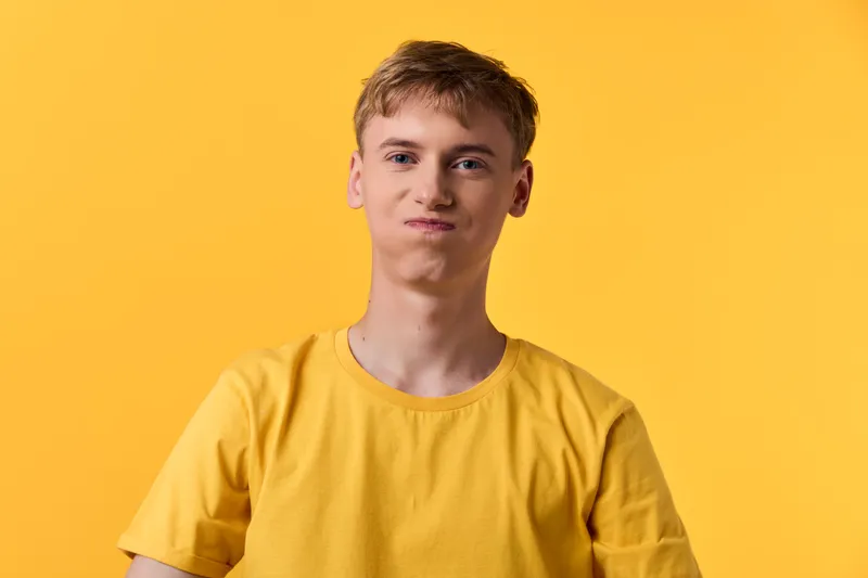 Young man in a yellow t shirt on a solid yellow backdrop, casual pose, minimal studio shot highlighting bright color harmony and relaxed mood for fashion visuals