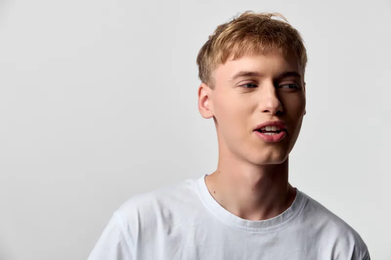 Young man in a white tshirt with a calm expression against a neutral background, casual style and relaxed pose for lifestyle, fashion and everyday wear concepts