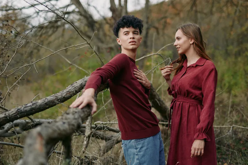 Two individuals share a candid moment in a rustic setting, their calm posture and natural gaze conveying authenticity and sincere connection amid autumn hues.