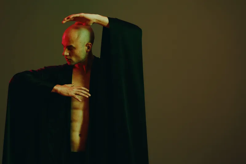 Dramatic man performing, showcasing strong emotions and striking pose against a muted background with soft lighting. Perfect for artistic representation and expression.