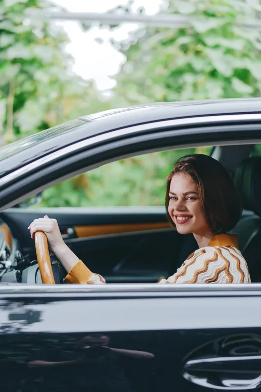 Car, driver, woman, smile a confident woman sits behind the wheel with a bright smile, hands on the steering wheel, radiating joy and readiness for a pleasant journey ahead