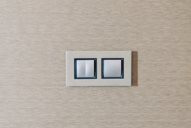 Double switch and light switch on a wooden wall, showcasing minimalist interior design and clean lines, a simple electrical fixture in a calm room.