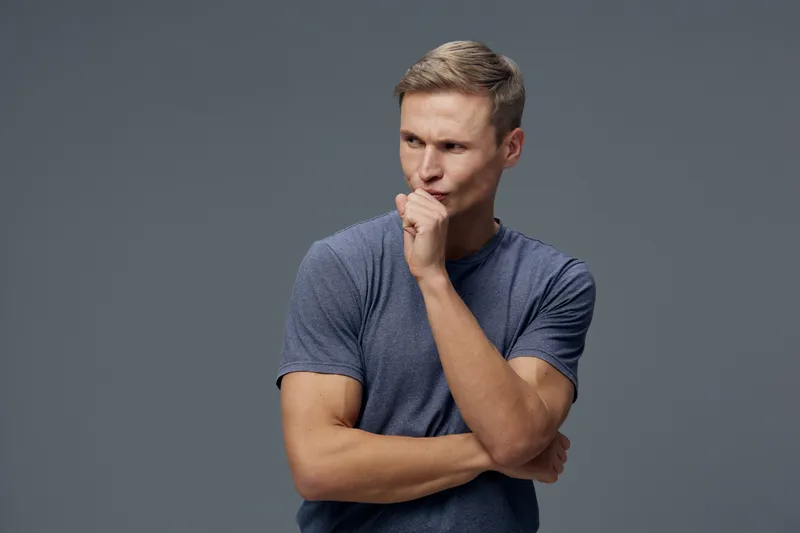 Thoughtful man with grey shirt look away think in doubt pose isolated on grey background studio portrait mental health concept and technology