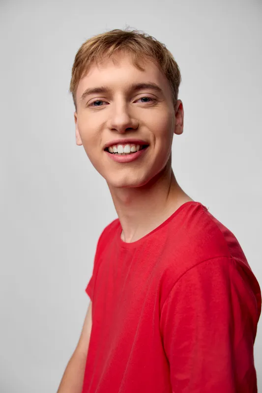 Smiling man in a red shirt, casual wear, friendly expression and upbeat energy against a neutral background, ideal for lifestyle and stock imagery conveying approachability and positive vibes