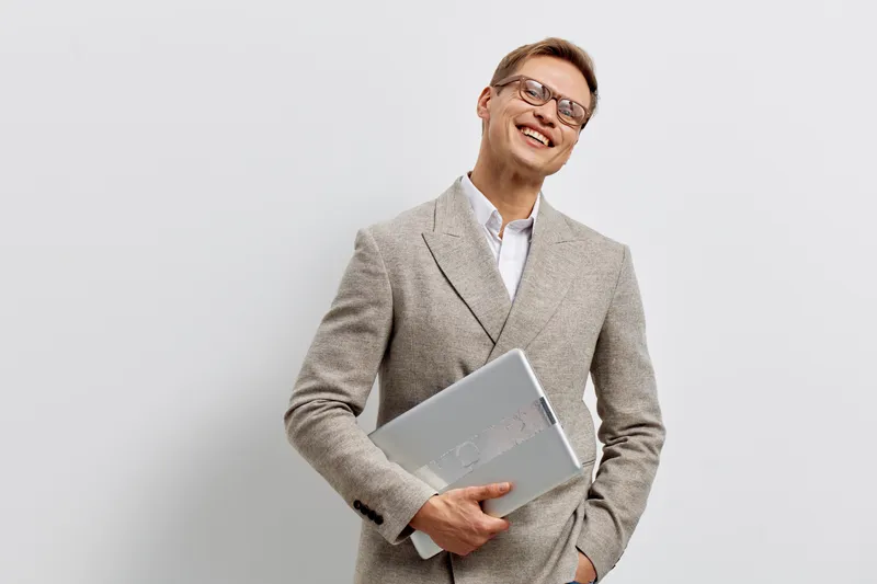 smiling man with laptop in beige plaid suit glasses isolated on grey background digital nomad freelance work concept