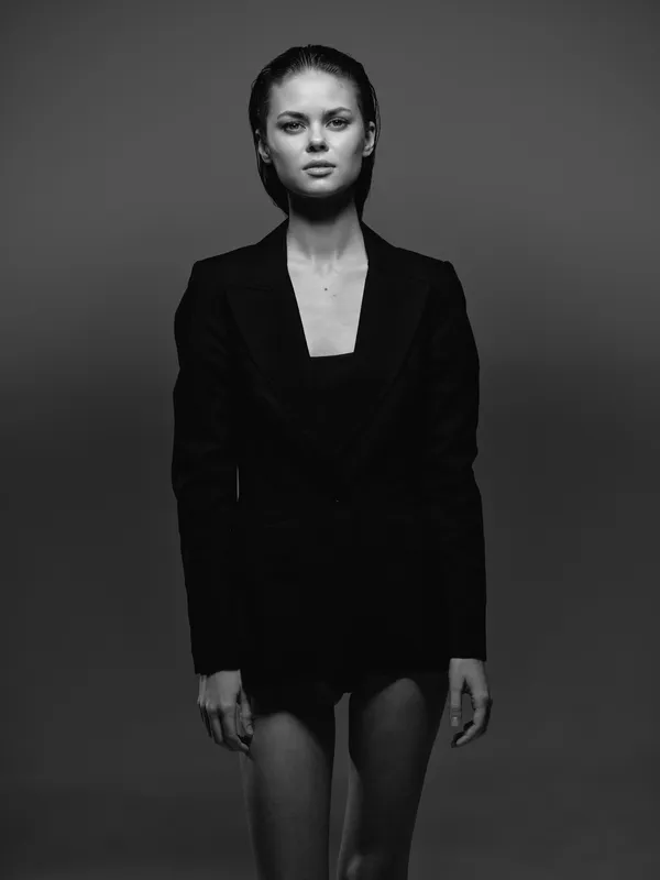 black and white portrait of a serious woman in a dark blazer with wet hair, minimalistic background and strong contrast