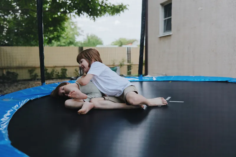 Playful children having fun on a trampoline, enjoying their childhood with laughter and joy. This lively scene captures the essence of carefree playtime.
