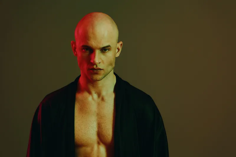 Striking image of a strong man posing dramatically, showcasing intense expression and unique lighting with a blend of red and green tones.