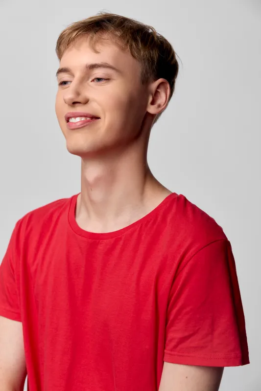 Smiling man in a red shirt in a clean studio setting, showcasing casual style, relaxed posture and warm expression for lifestyle, fashion, and everyday stock imagery