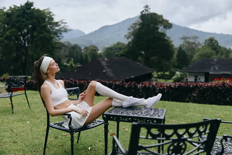 Young woman enjoying outdoor relaxation in sporty attire, surrounded by nature, evoking feelings of tranquility and well being