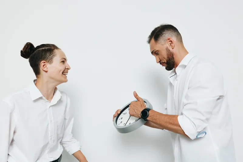 Professional business scene with a confident man and a smiling colleague against an isolated white background, conveying collaboration, focus, and subtle positive emotion.