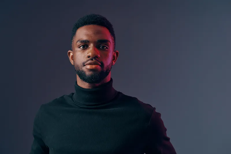 Portrait of a serious African male model in a black turtleneck sweater against a gradient grey background, conveying confidence and style, ideal for fashion and lifestyle concepts