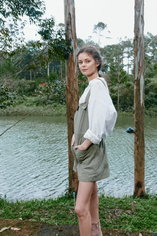 Young woman in casual outfit by the lake, exuding serenity and connection with nature, dressed in light colors, ideal for promoting outdoor lifestyle and wellness