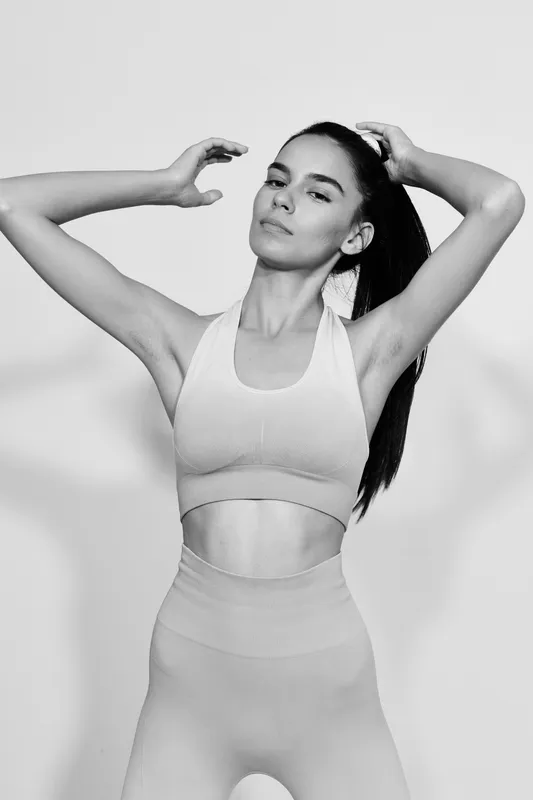 Black and white woman sport fitness portrait in seamless activewear, showing athletic physique and focused expression, emphasizing wellness and strength.