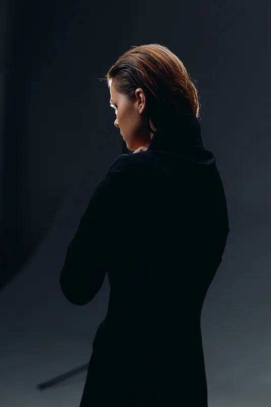 Portrait of a woman in black turtleneck with thoughtful expression on dark background