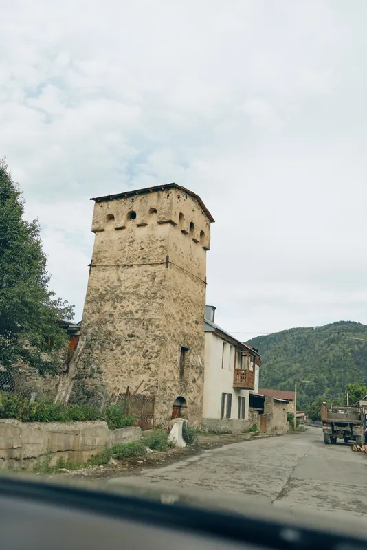 Tower village stone house on rural road with mountains