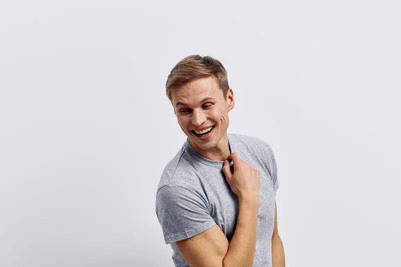 smiling man in casual gray t-shirt looking aside with happy cheerful expression isolated on plain white background digital detox concept mental health and gadgets