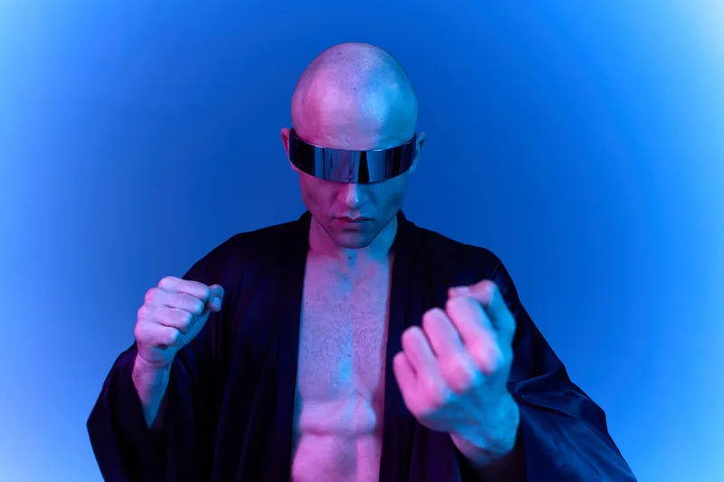 Futuristic man in a black robe, showcasing strength with clenched fists and vivid blue lighting. The image conveys a sense of power and determination.