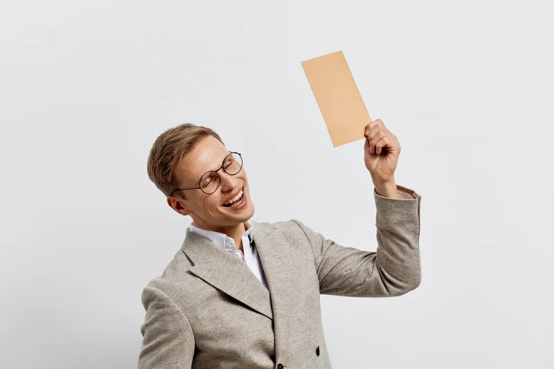 Happy smiling young caucasian man wear striped suit hold blank paper card isolated on light gray background business concept digital nomad work remote office