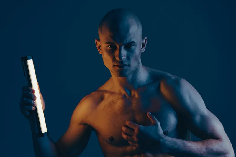 Intense man holding light source, showcasing strength and determination in a dramatic, low-key lighting setup. Captivating, dynamic, and expressive portrait image.